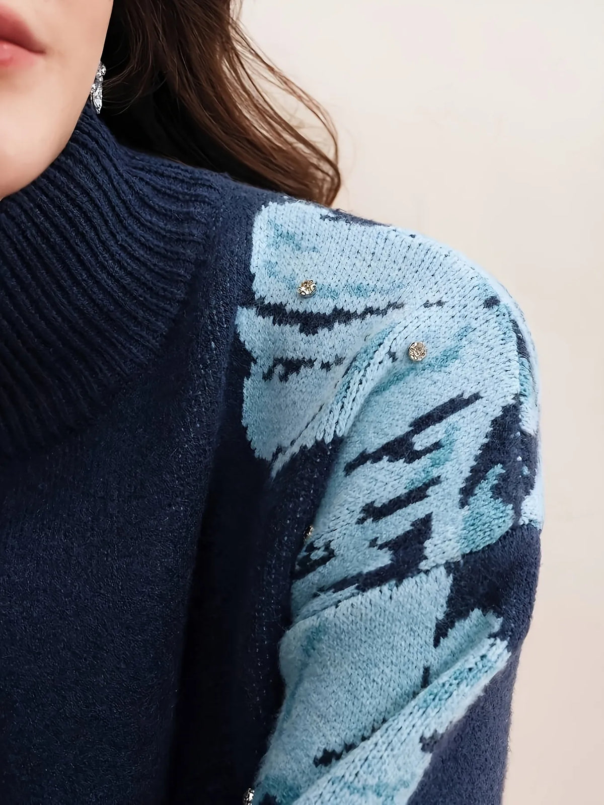 Navy blue sweater with a patterned sleeve on a neutral background