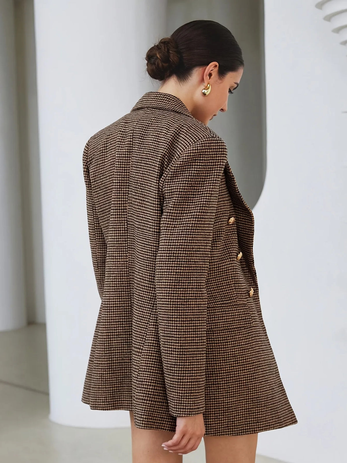 Woman wearing a brown checkered blazer in an indoor setting