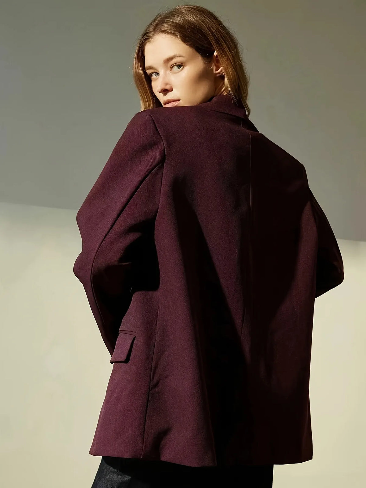 Woman wearing a burgundy coat against a neutral background