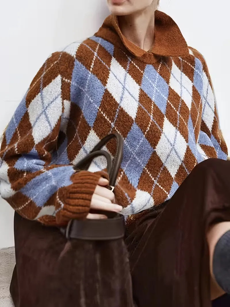 Person wearing a brown, blue, and white argyle patterned sweater holding a black handbag.