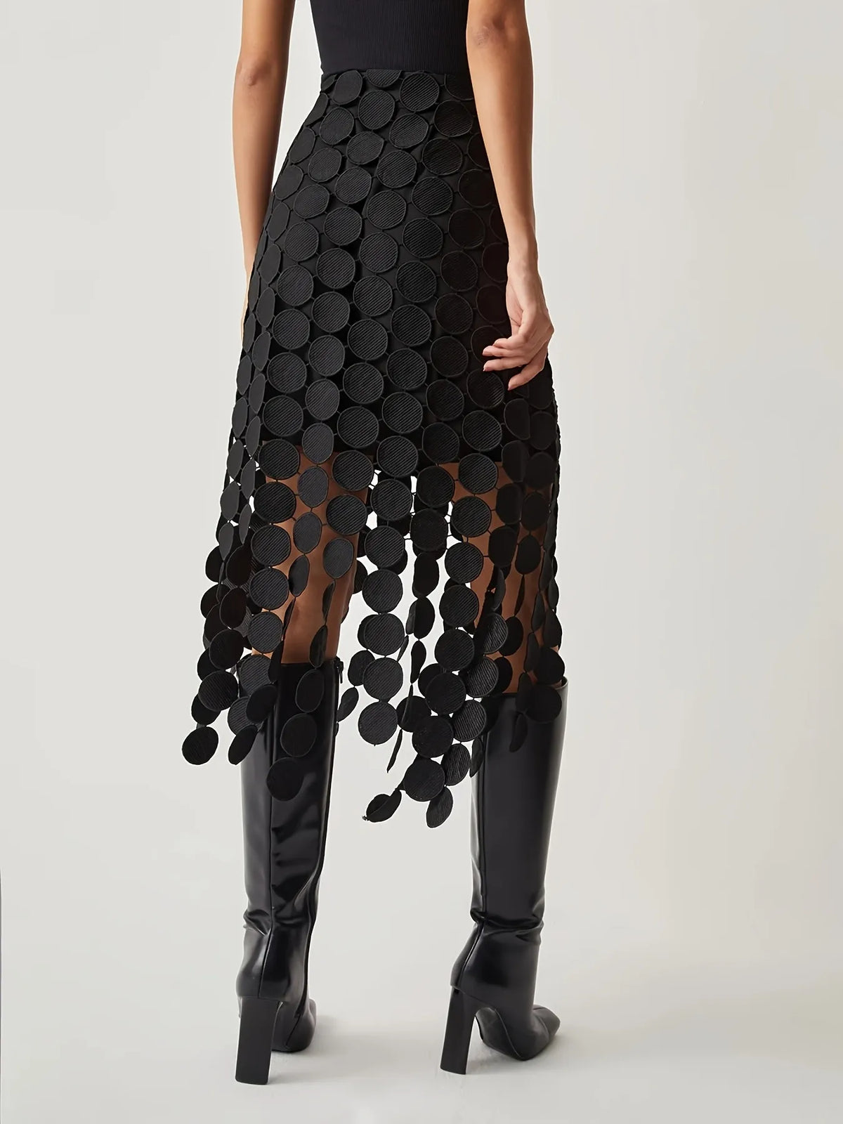 Black patterned skirt worn by a person on a white background