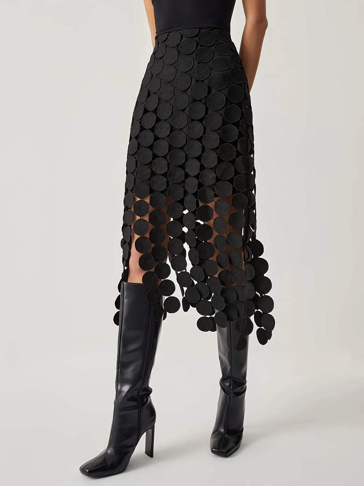 Black patterned skirt with cut-out design worn by a person on a light gray background