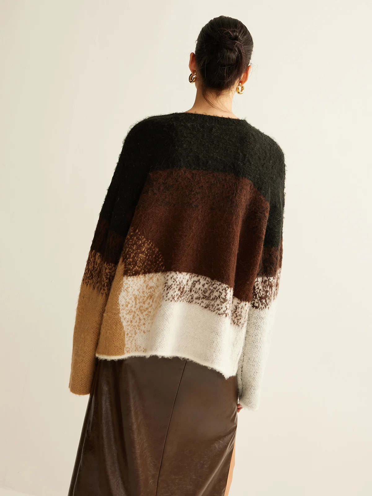 Person wearing a multicolored sweater with a neutral background