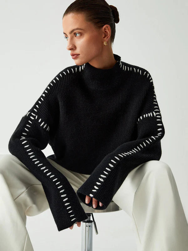 Woman wearing a black sweater with white stitching on a white background