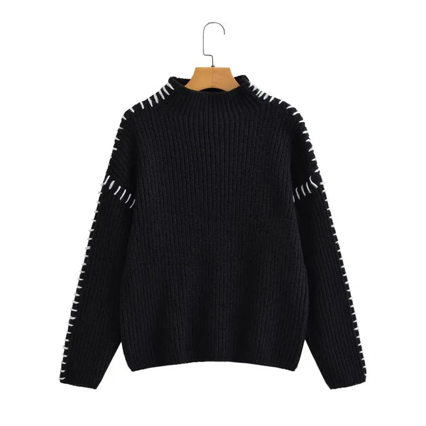 Black sweater with white trim on a hanger against a white background