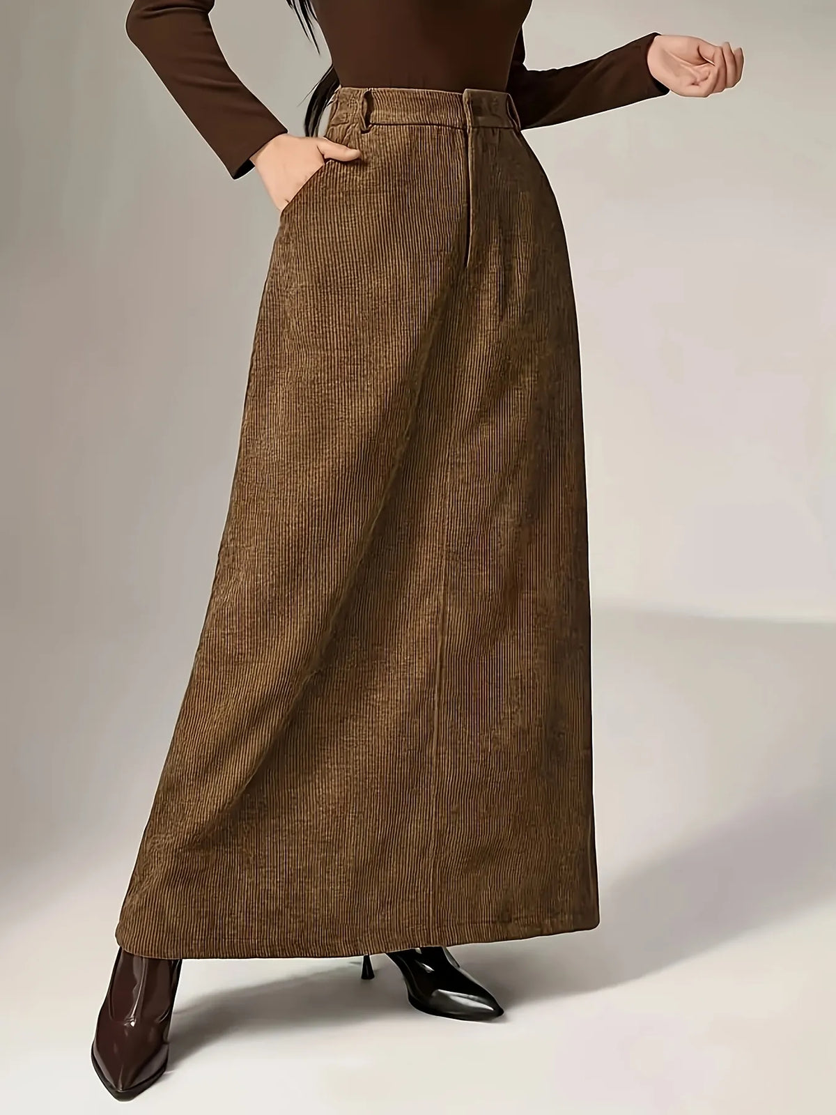 Person wearing a brown ribbed sweater and wide-leg brown pants on a plain background