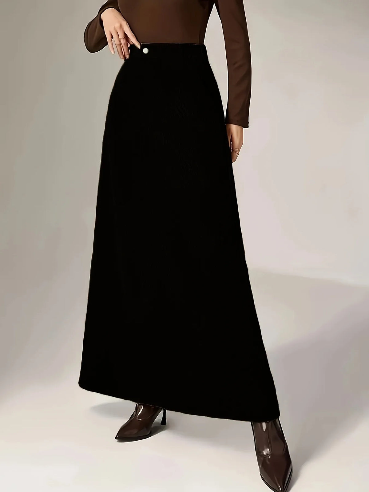 Person wearing a long black skirt with a plain background