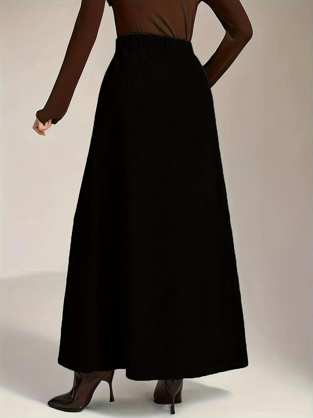 Person wearing a long black skirt on a plain background