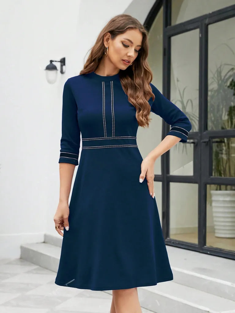 Woman wearing a navy blue dress with a subtle pattern, standing in an outdoor setting.