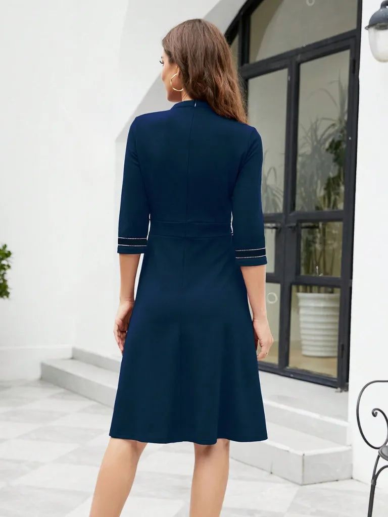Woman wearing a navy blue dress with white trim in an outdoor setting.
