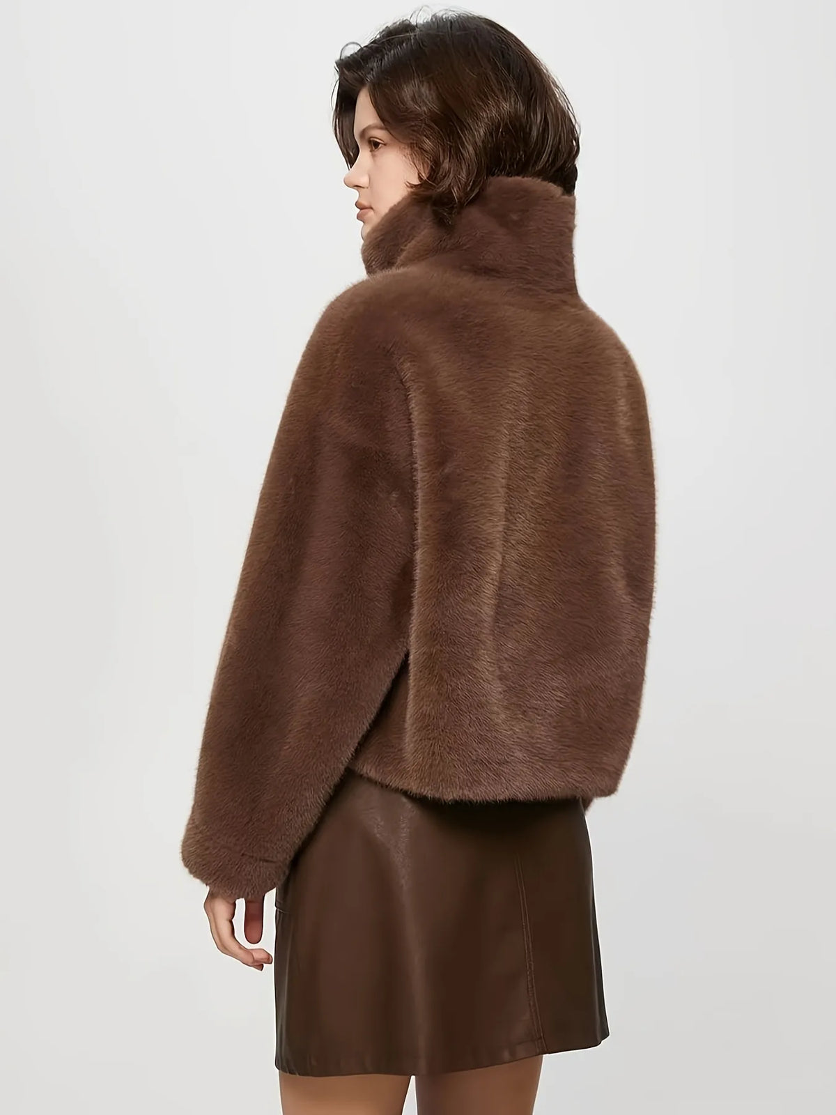 Person wearing a brown fur coat and leather skirt on a white background