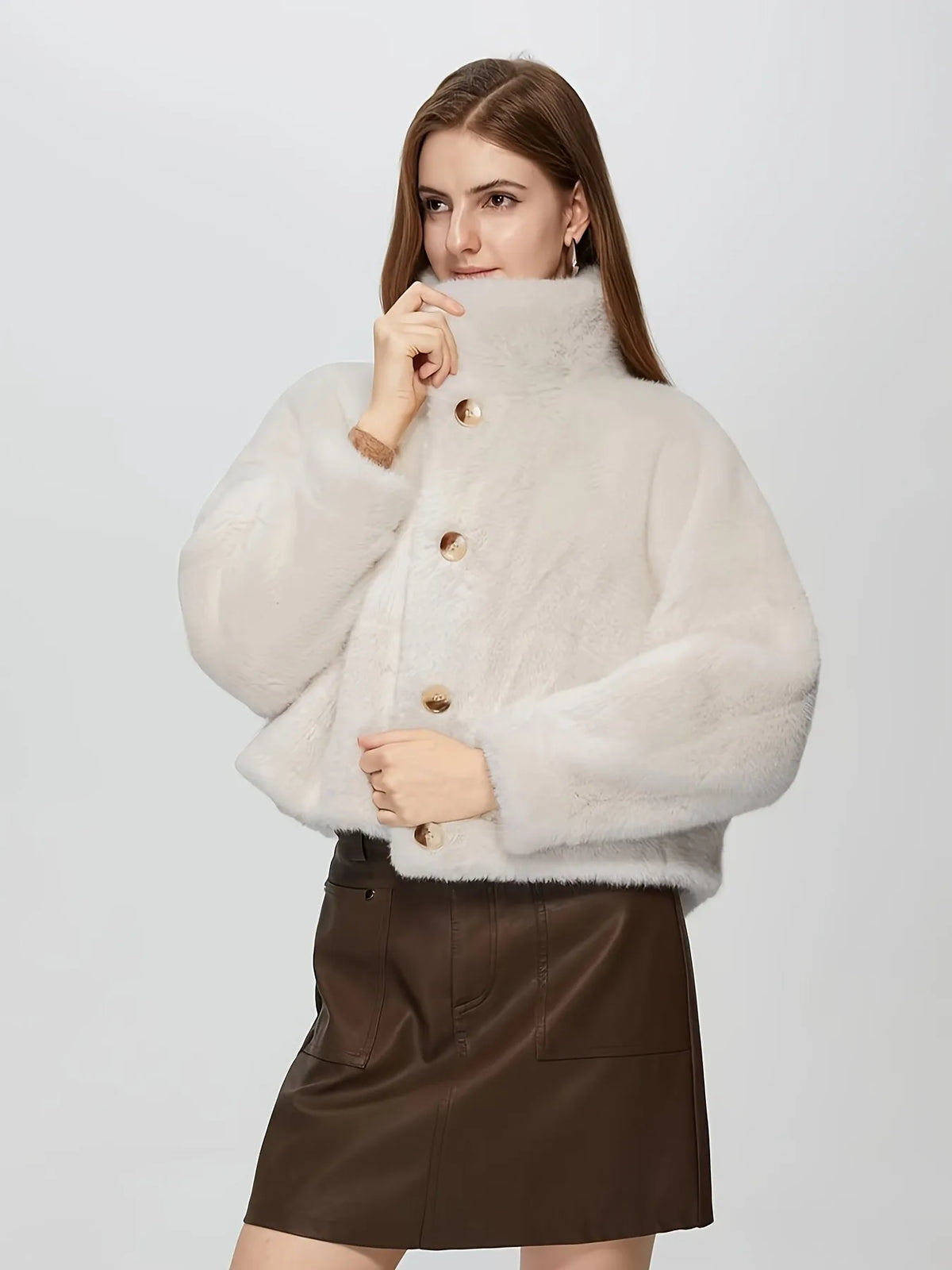 Woman wearing a light beige fluffy jacket with gold buttons on a white background