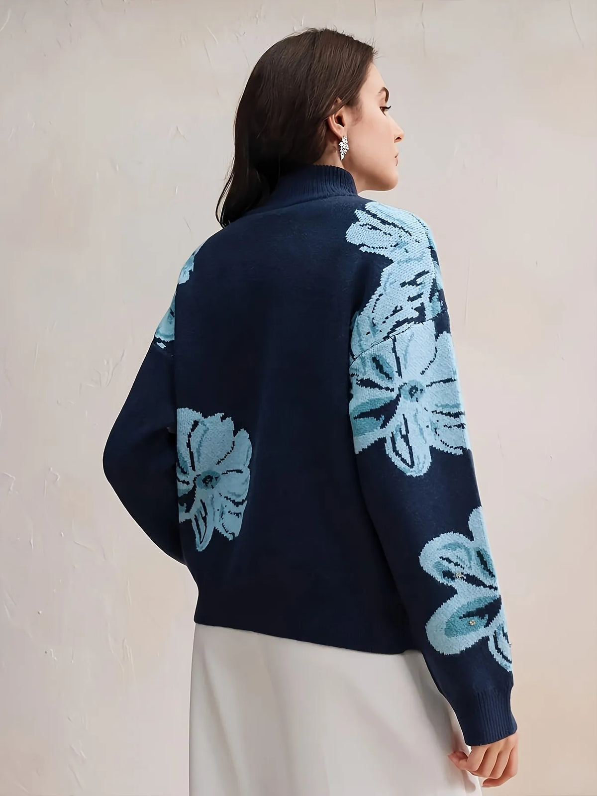 Woman wearing a dark blue cardigan with light blue floral patterns on a beige background
