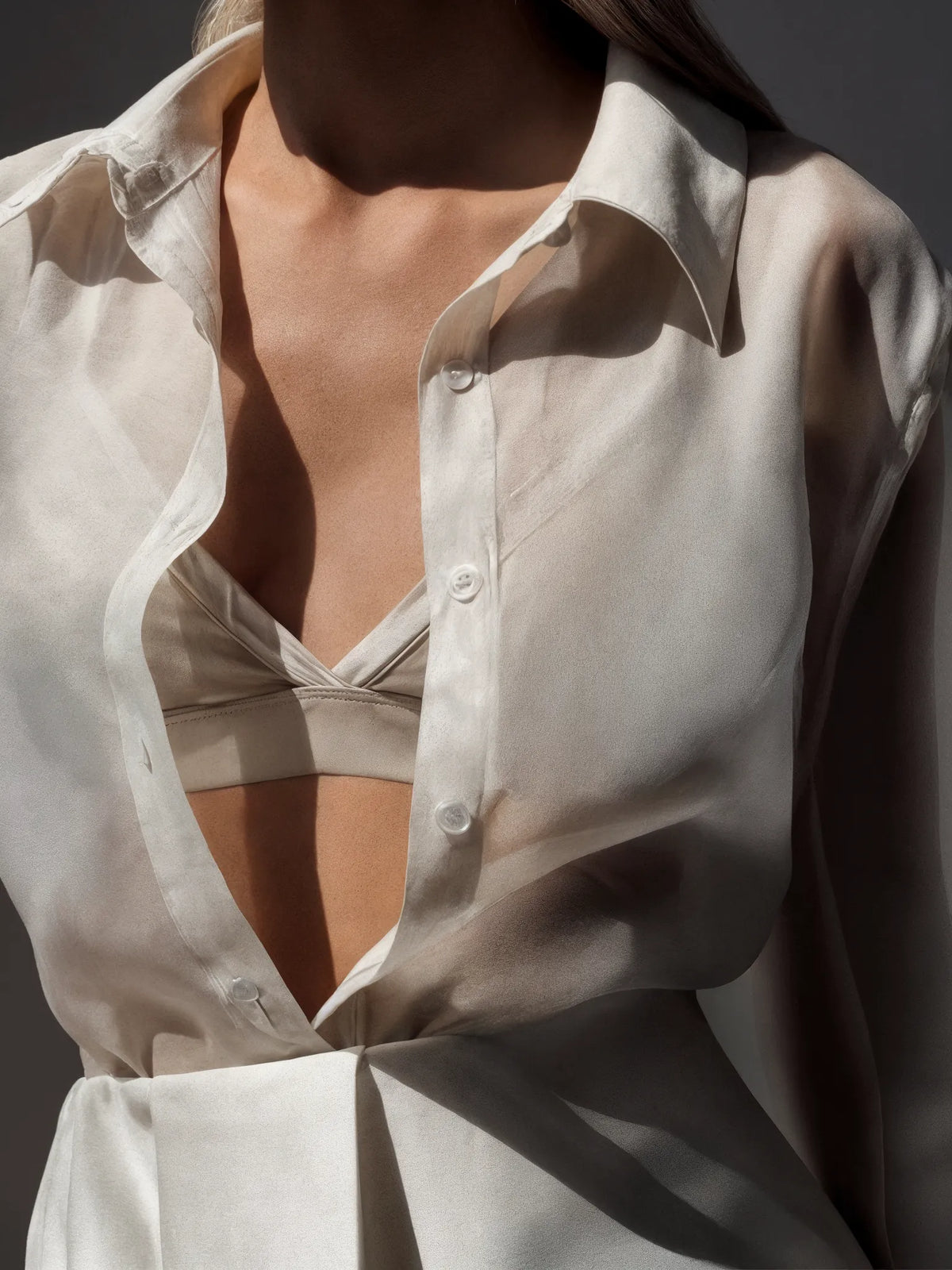 Close-up of a person wearing an open white shirt against a dark background