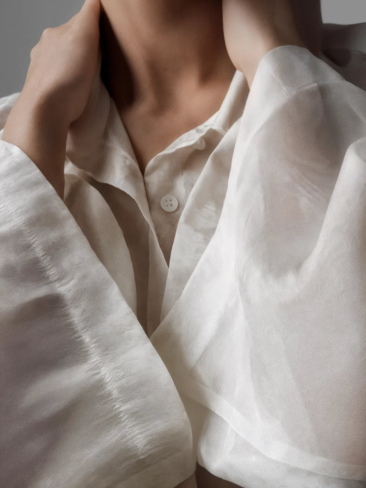 Close-up of a person wearing a white shirt with a neutral background