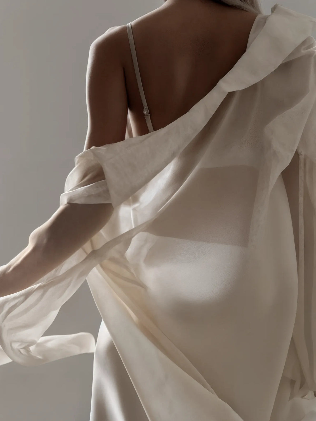Person wearing a flowing white garment with a neutral background