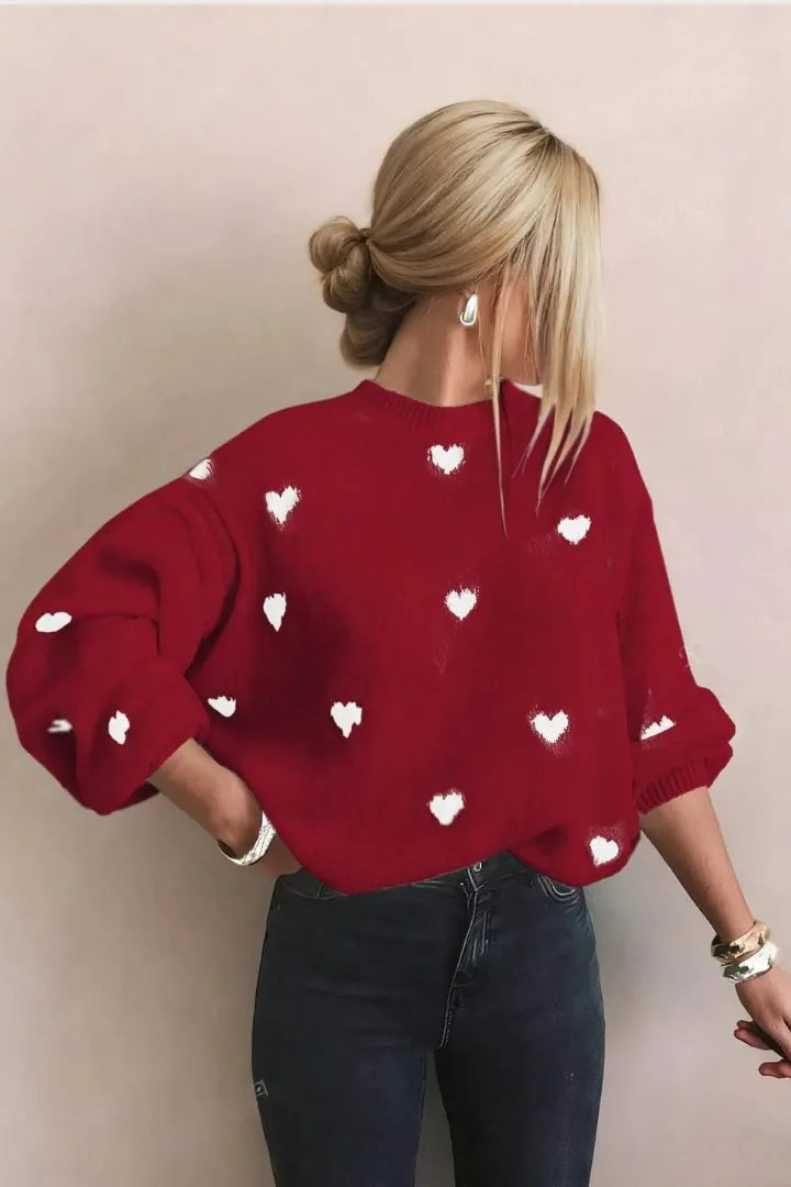 Person wearing a red sweater with white heart patterns against a beige background