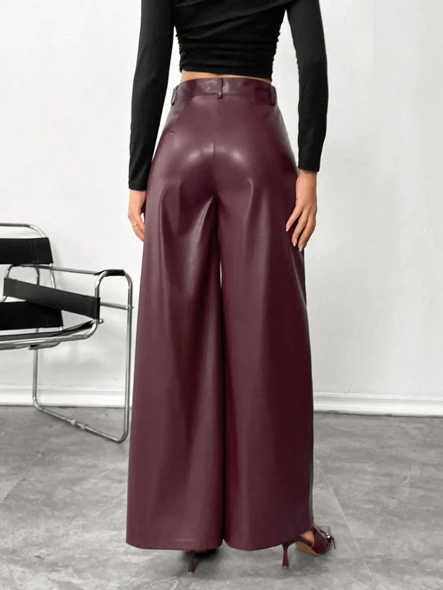 Person wearing burgundy leather pants with a black top against a white background