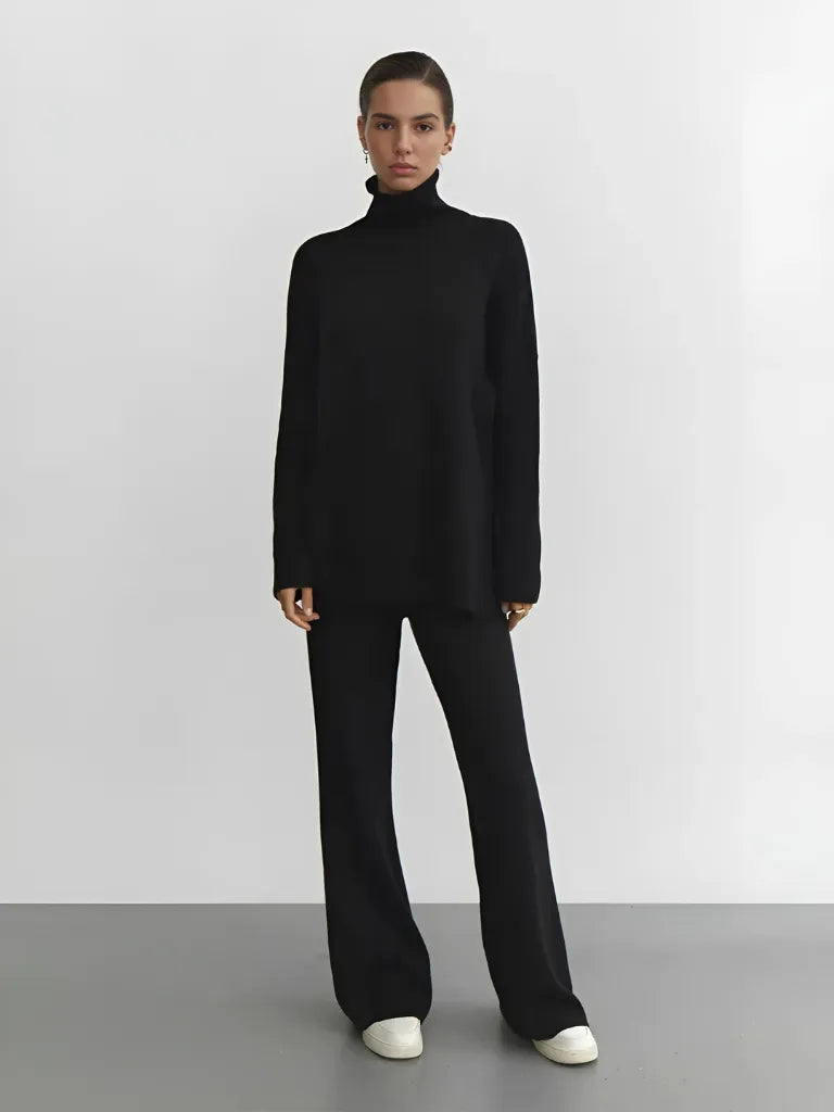Person wearing a black turtleneck and black pants on a plain background