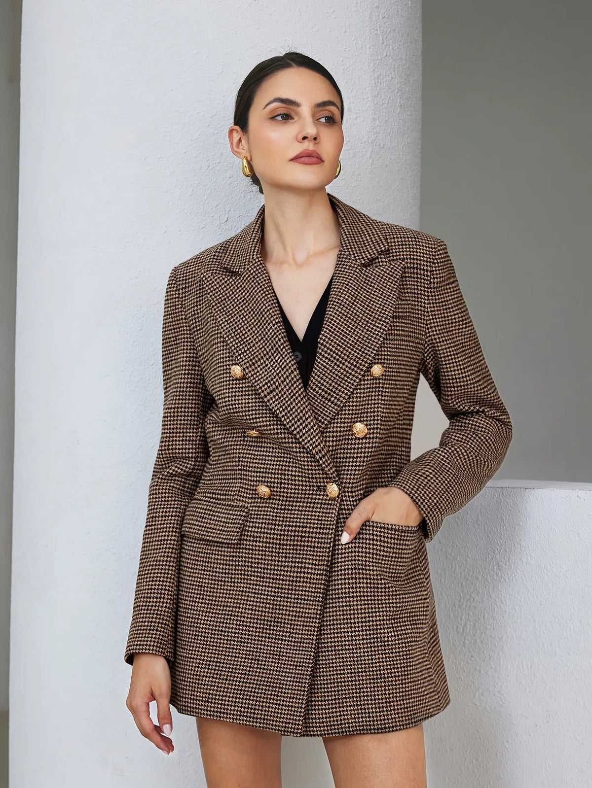 Woman wearing a brown checkered blazer over a black top against a neutral background