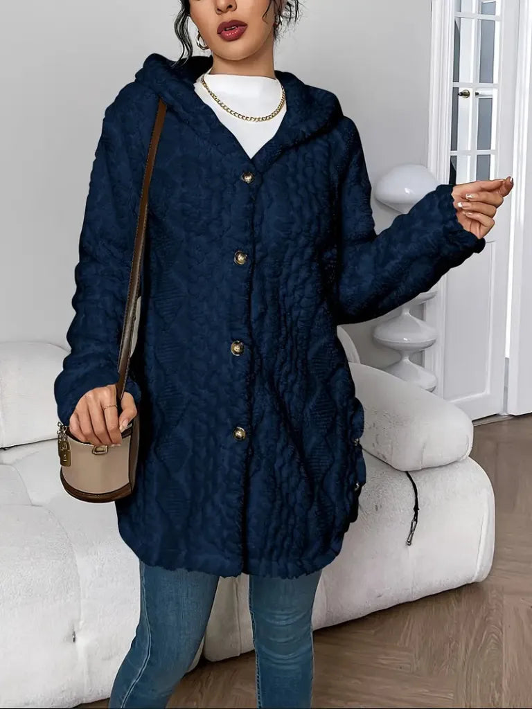 Person wearing a blue textured coat in a room with white furniture.