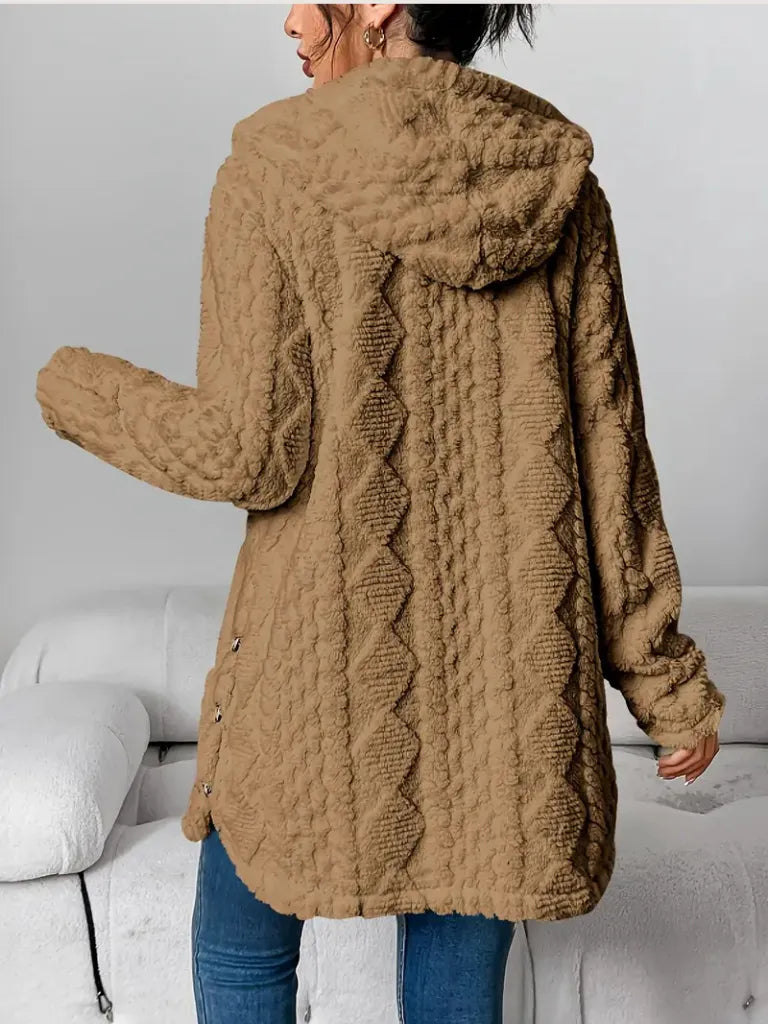 Person wearing a brown textured coat in a minimal indoor setting