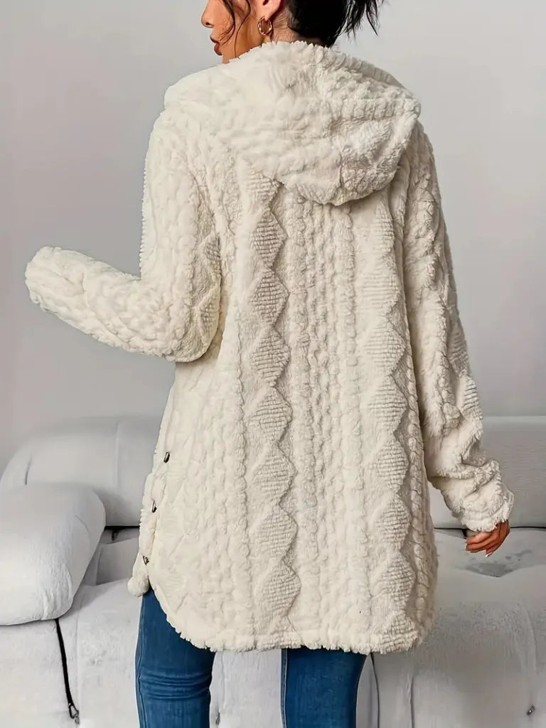 Person wearing a white textured coat in a minimal indoor setting