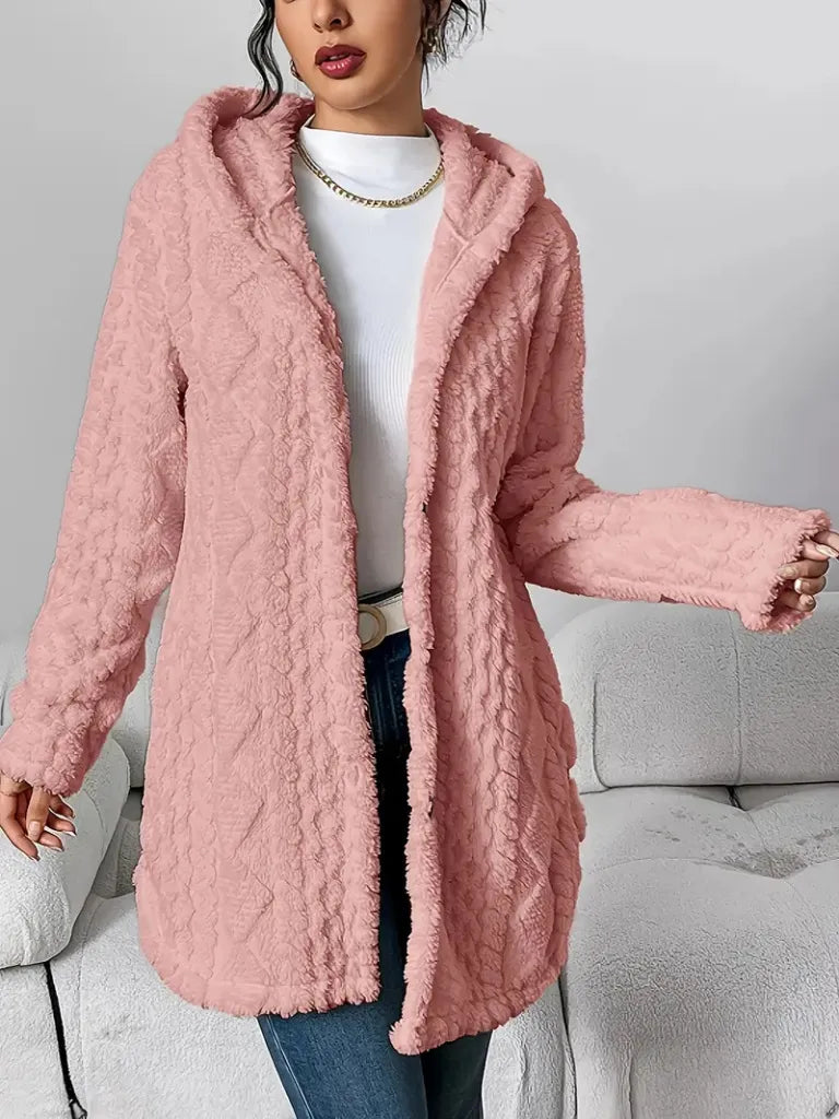 Person wearing a pink textured coat in a neutral setting