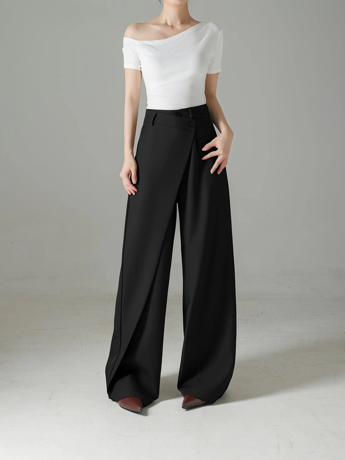 Person wearing a white top and black wide-leg pants on a plain background