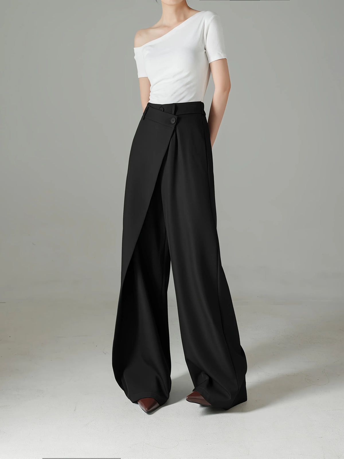 Person wearing a white top and black wide-leg pants on a gray background