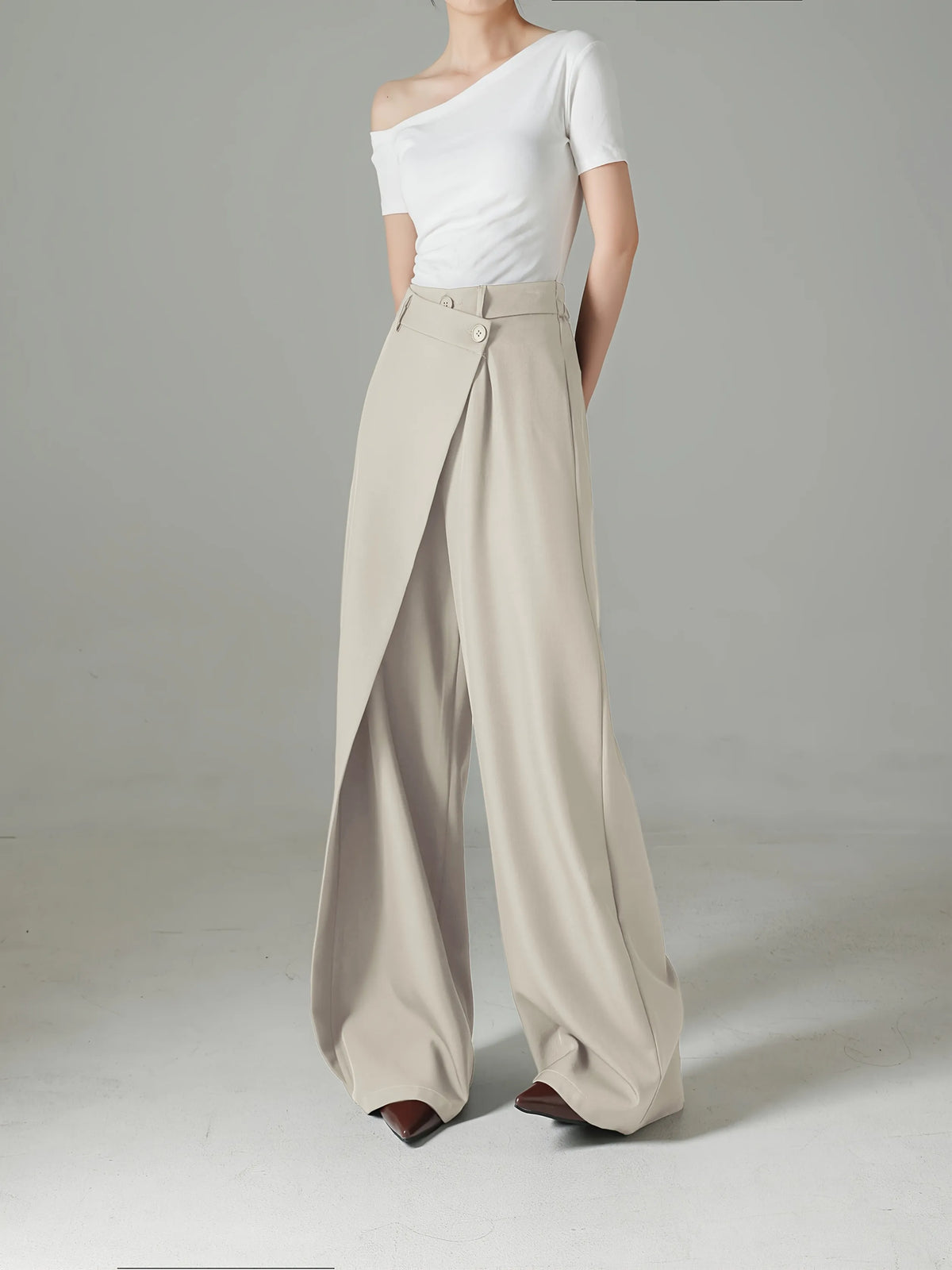 Person wearing a white top and beige wide-leg pants on a gray background
