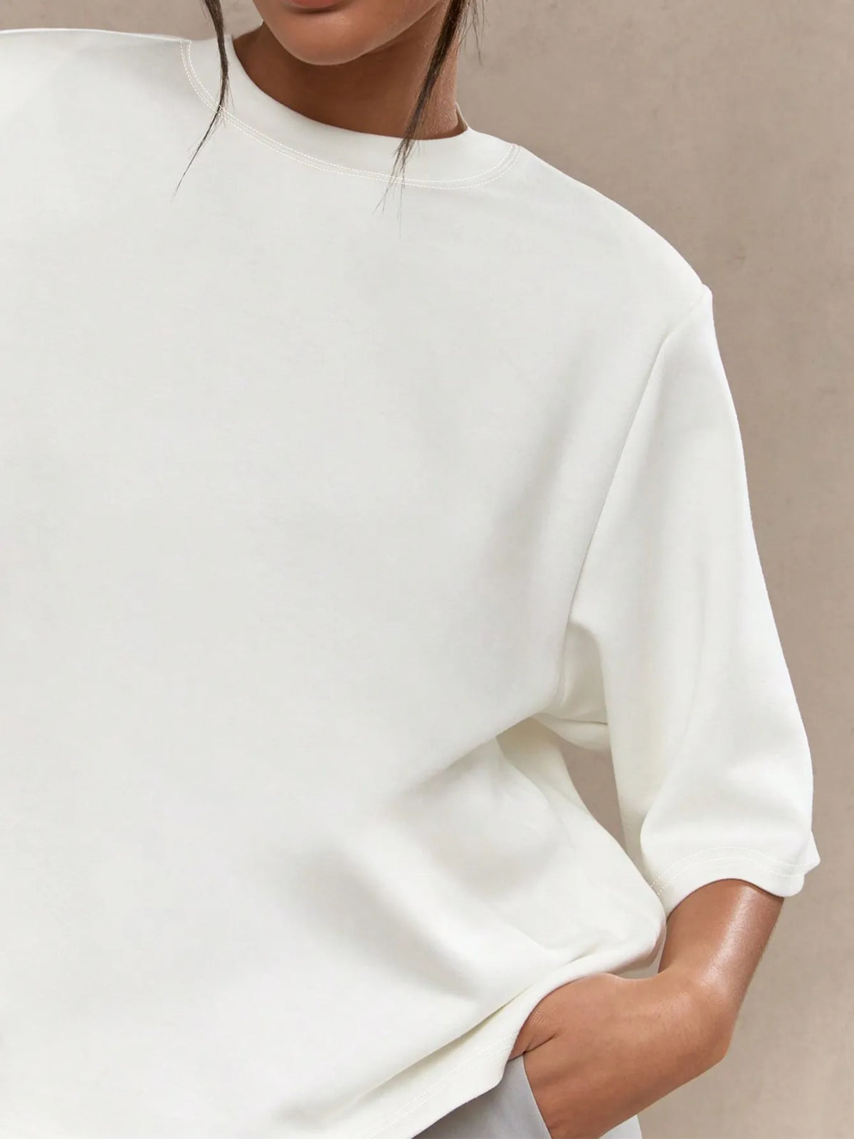 Person wearing a white outfit with a neutral background