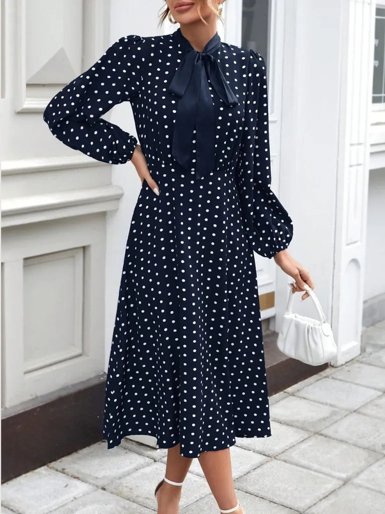 Woman wearing a navy polka dot dress with a white background