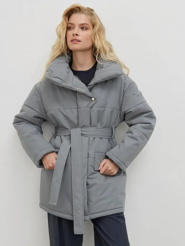 Woman wearing a gray coat with a belt against a white background