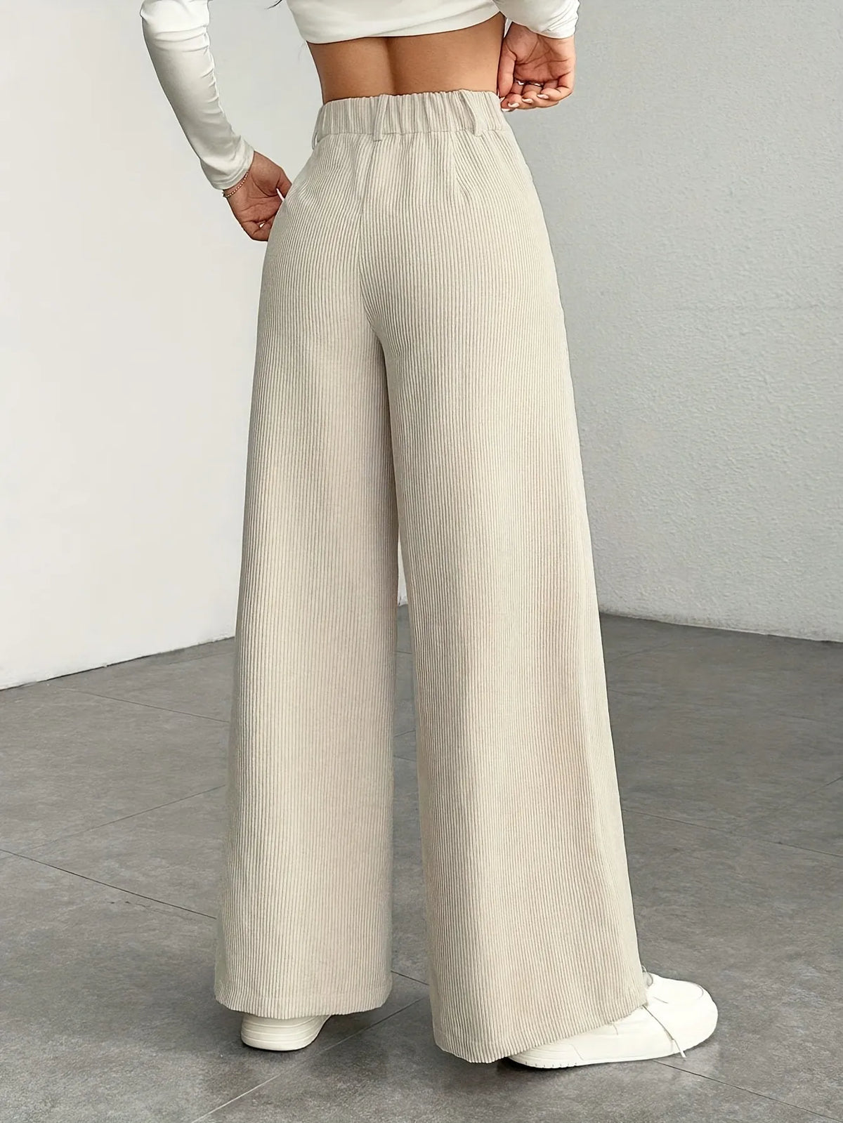 Person wearing beige wide-leg pants on a plain background