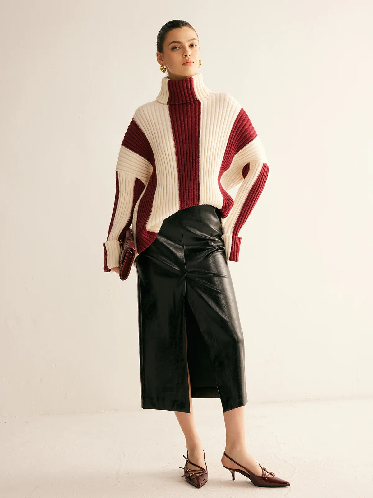 Woman wearing a striped sweater and black leather skirt on a plain background
