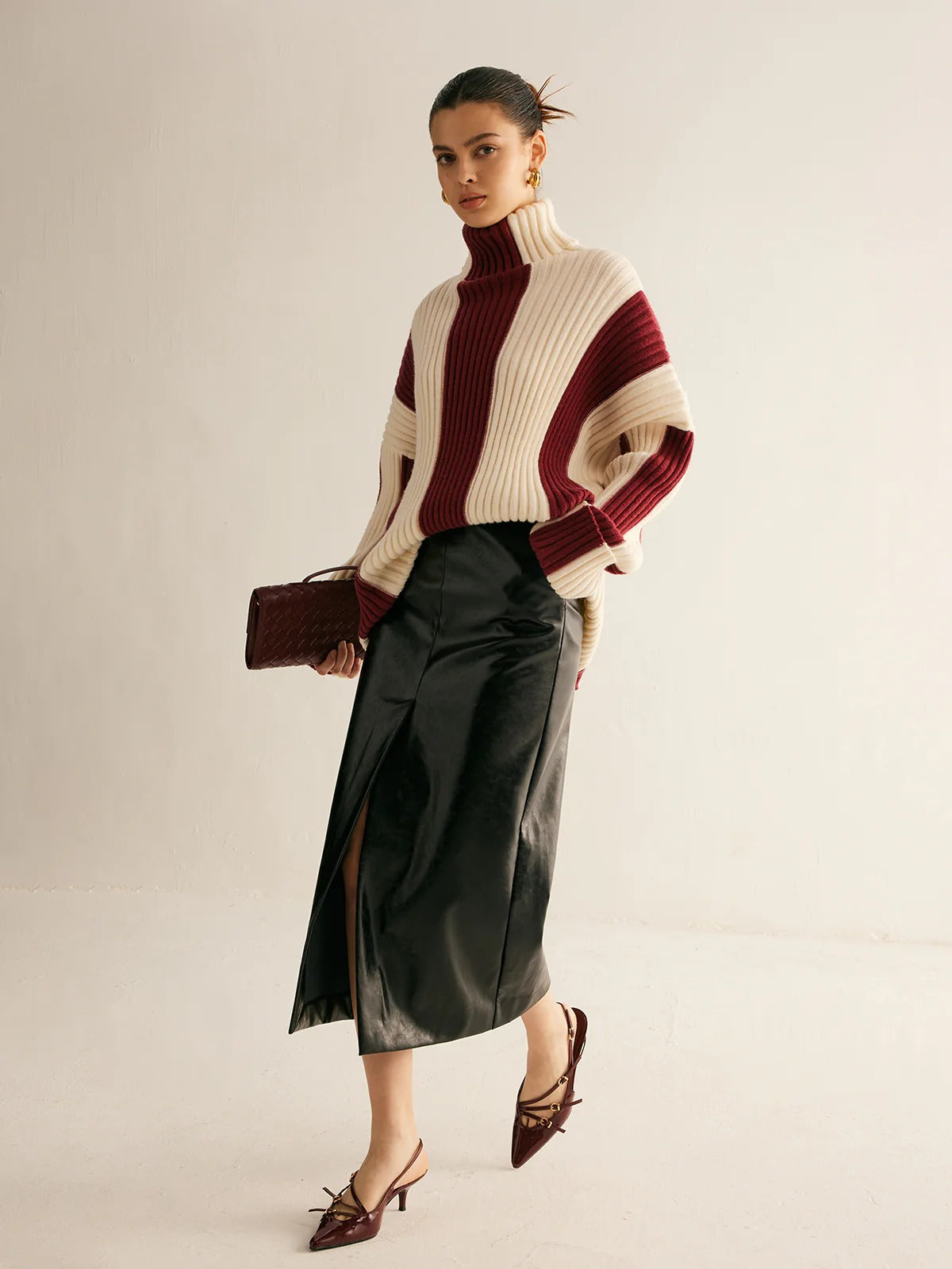 Woman wearing a two-tone sweater and black skirt on a plain background