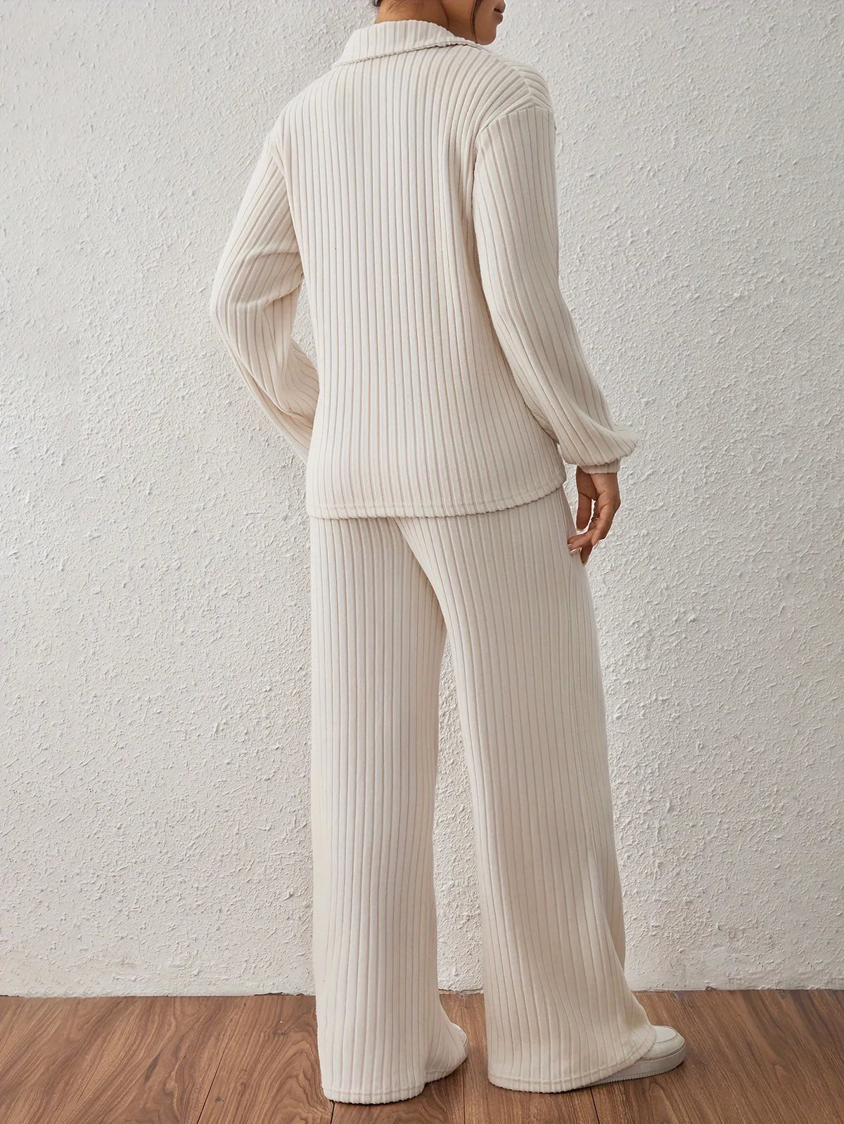 Person wearing a ribbed knit outfit against a white wall