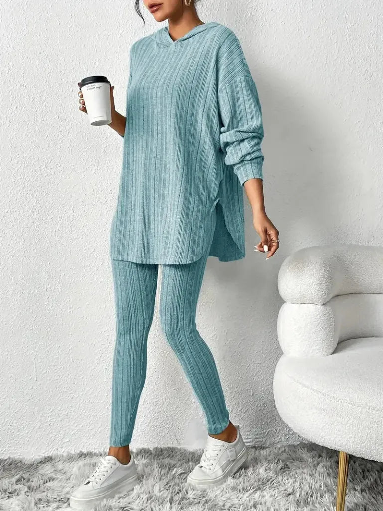 Person wearing a teal ribbed lounge set holding a coffee cup against a white background.