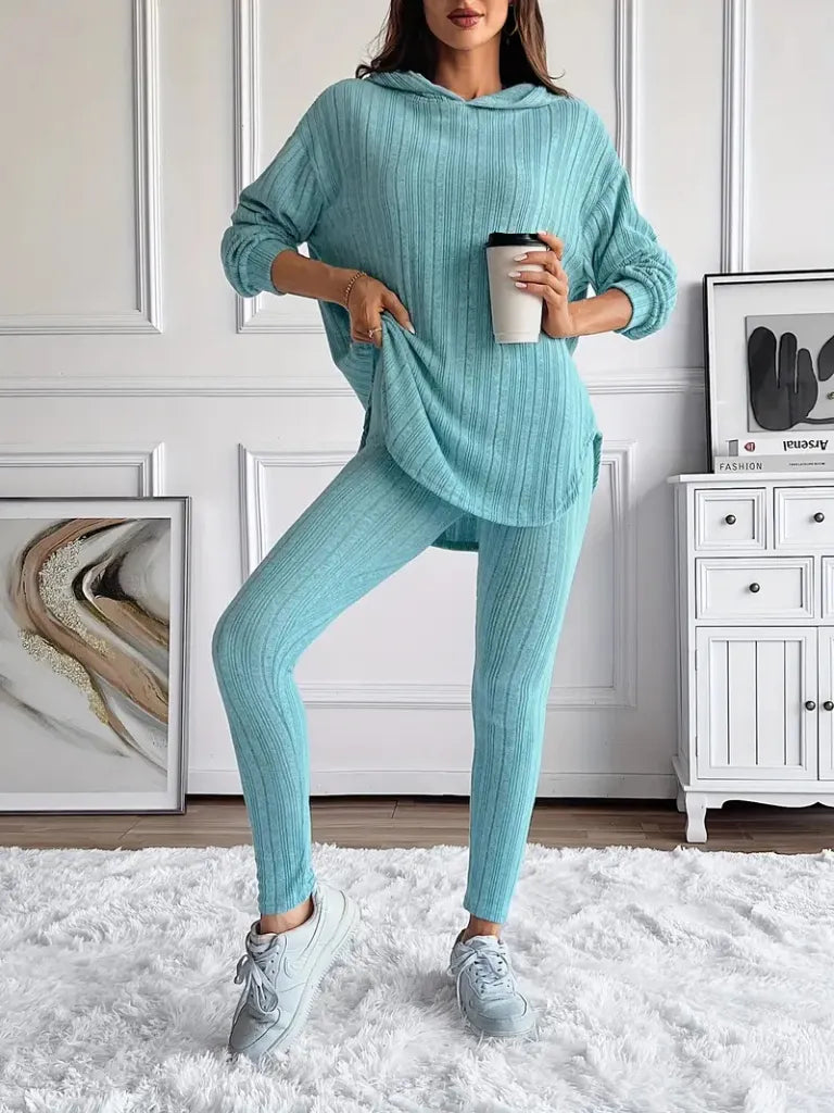 Person wearing a teal ribbed loungewear set holding a coffee cup indoors.