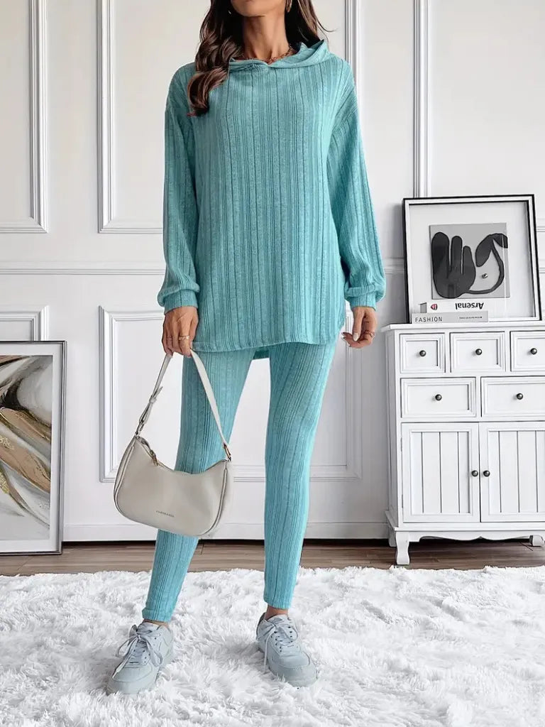 Person wearing a teal outfit with a white wall and furniture in the background