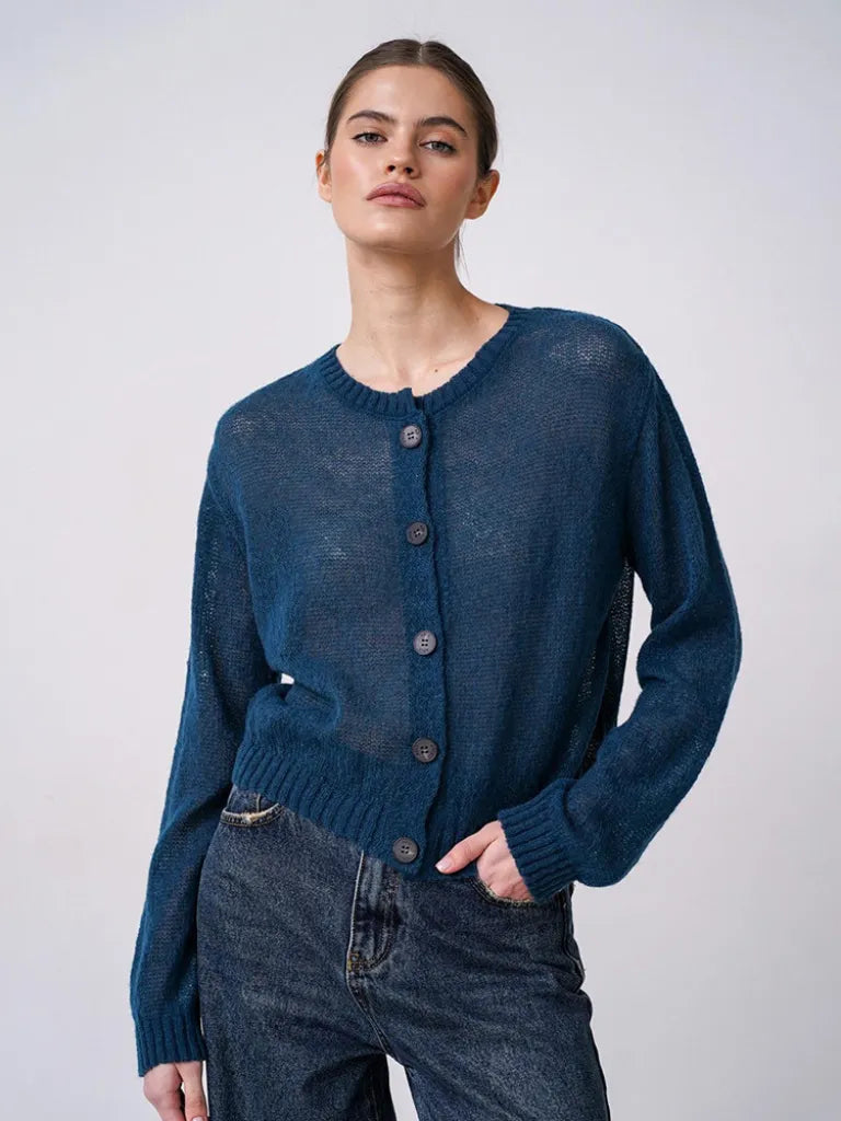 Woman wearing a blue cardigan against a plain background