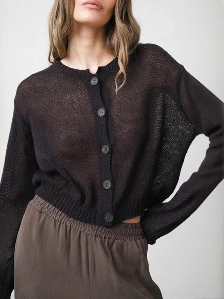 Person wearing a dark brown cardigan and pants on a plain background