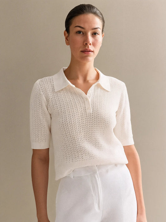 Woman wearing a white knit top and white pants against a beige background