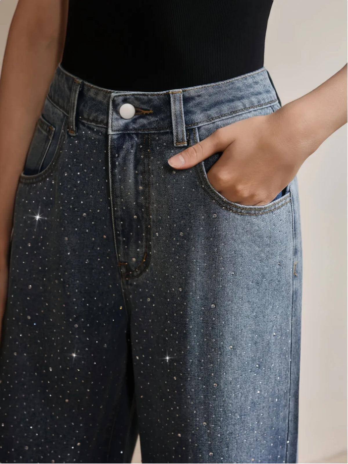 Close-up of a person wearing blue jeans with star patterns on a neutral background