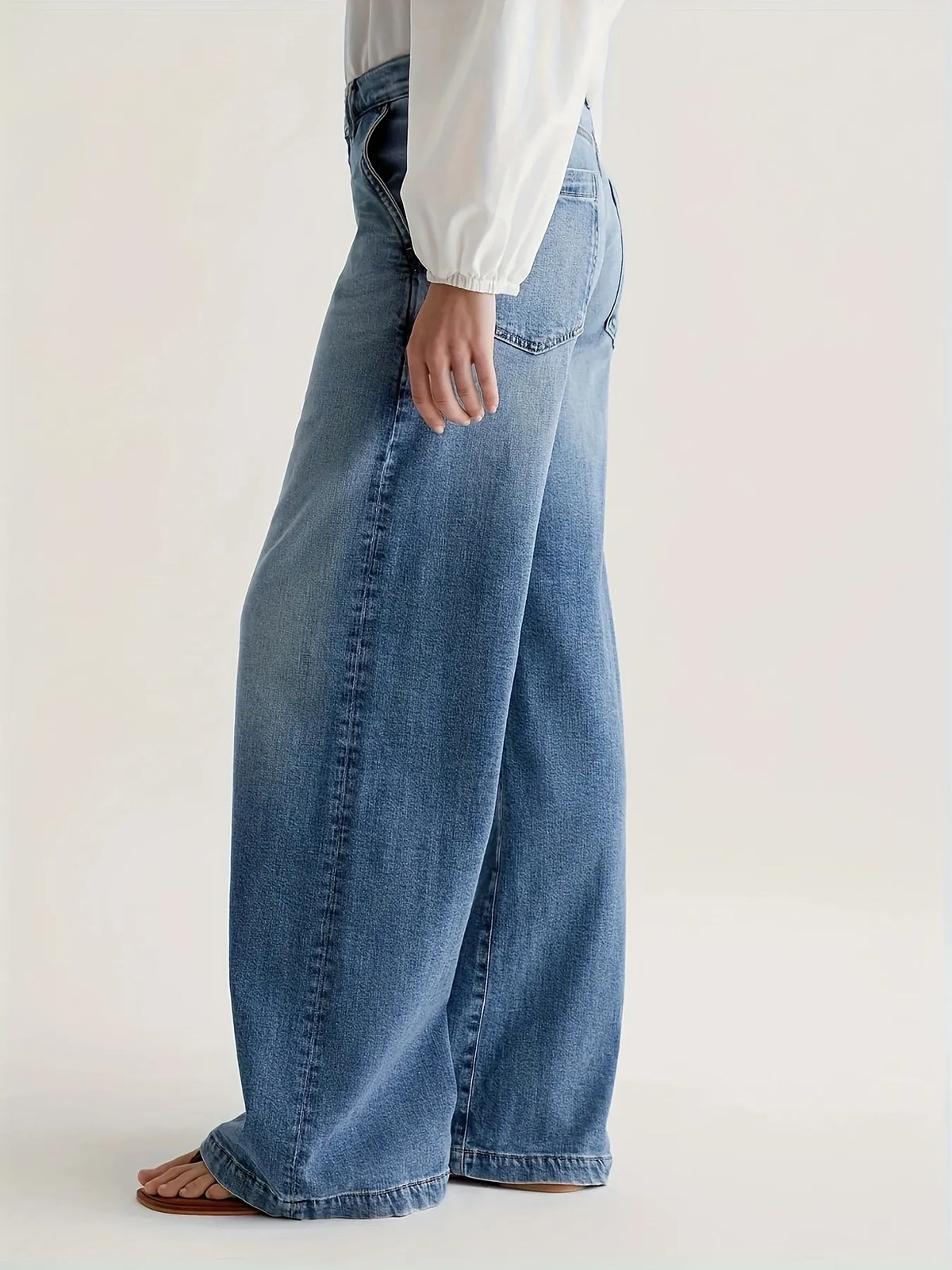 Person wearing blue jeans on a plain background
