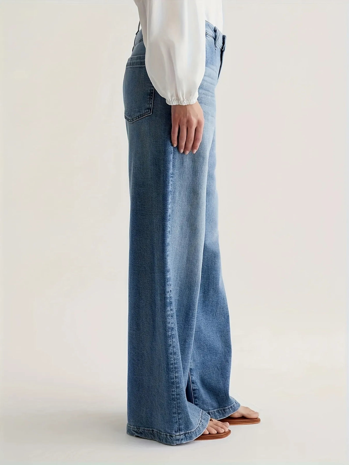 Person wearing light blue jeans and a white shirt on a plain background