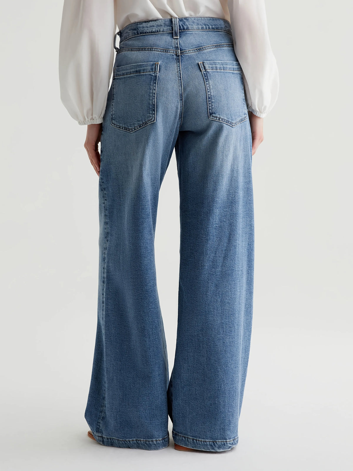 Person wearing blue jeans on a plain background