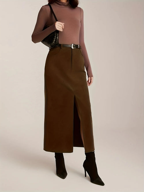 Person wearing a brown turtleneck and long skirt with black high-heeled boots on a plain background