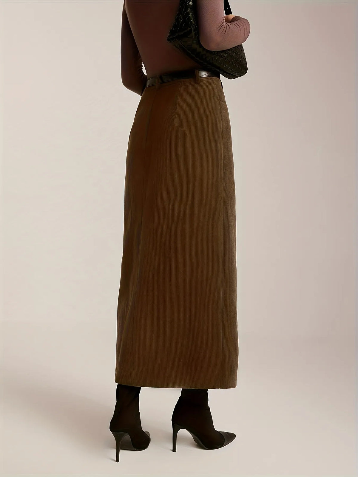 Person wearing a long brown skirt on a plain background
